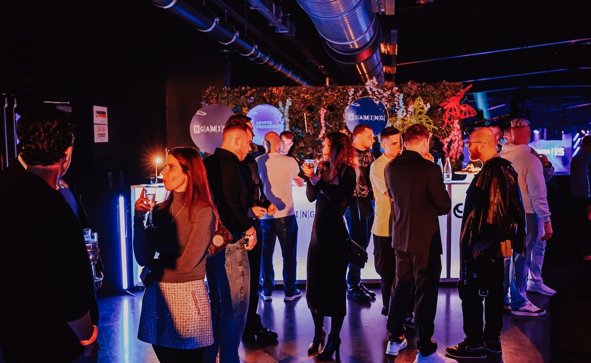 Guests mingling around a custom-branded corporate activation bar with illuminated logo signage.