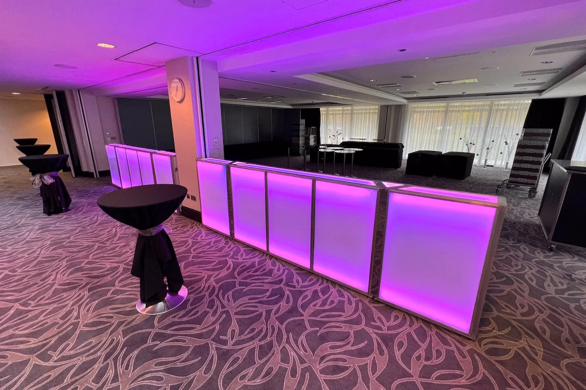 Purple LED illuminated 3.8m modular bar setups installed around pillars in a corporate indoor event suite.