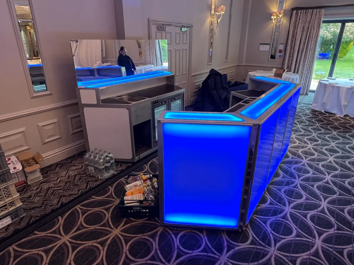 Blue LED modular mobile bar setup during venue preparation showing back-bar units and integrated refrigeration.